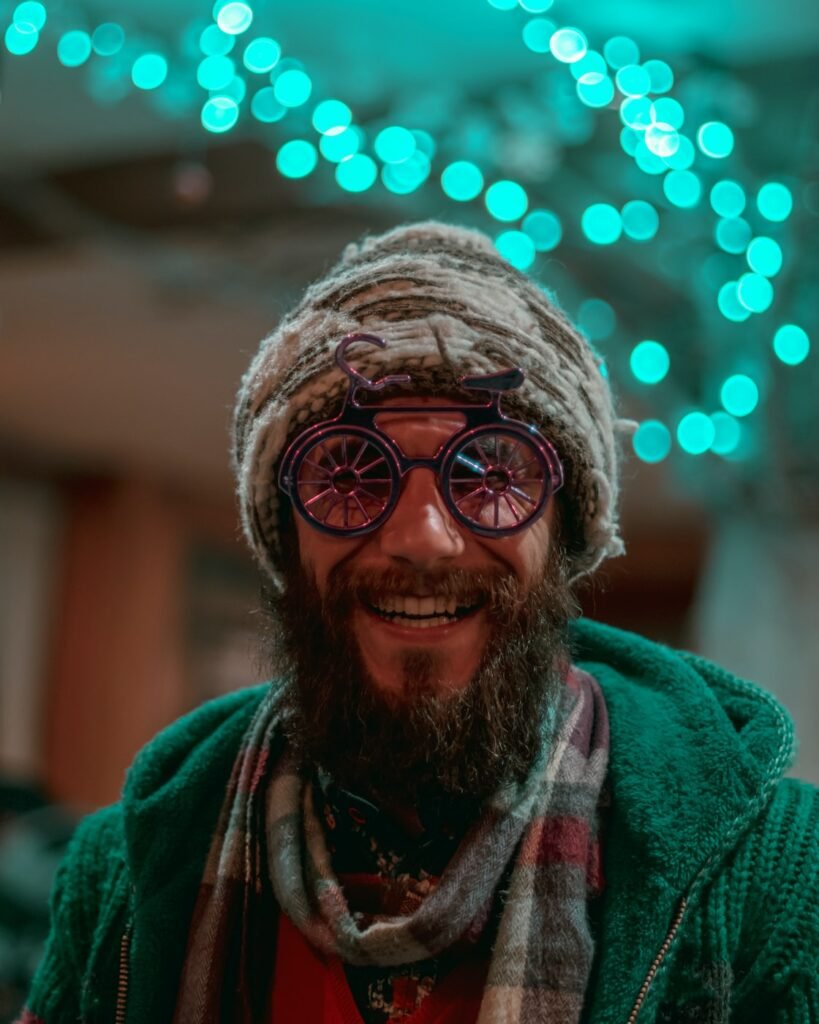 selective focus photography of man wearing gray knit cap, red-and-gray scarf and green cable knit zip hoodie