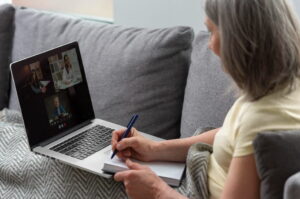 Adult woman taking notes during an online ADHD coaching session, reflecting on ADHD symptoms and late diagnosis